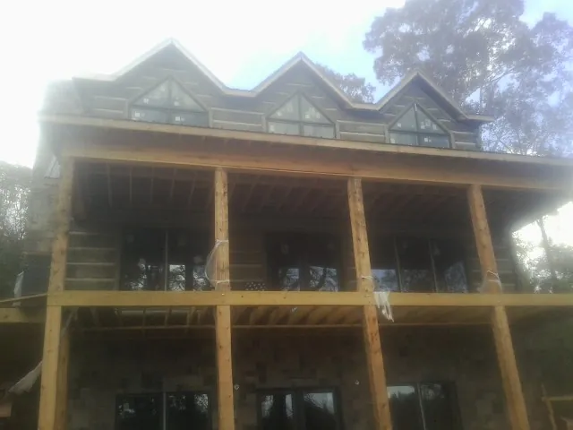 Dormers and porch framing on a large log home under construction — Roof Coating work by our crew in Petersburg